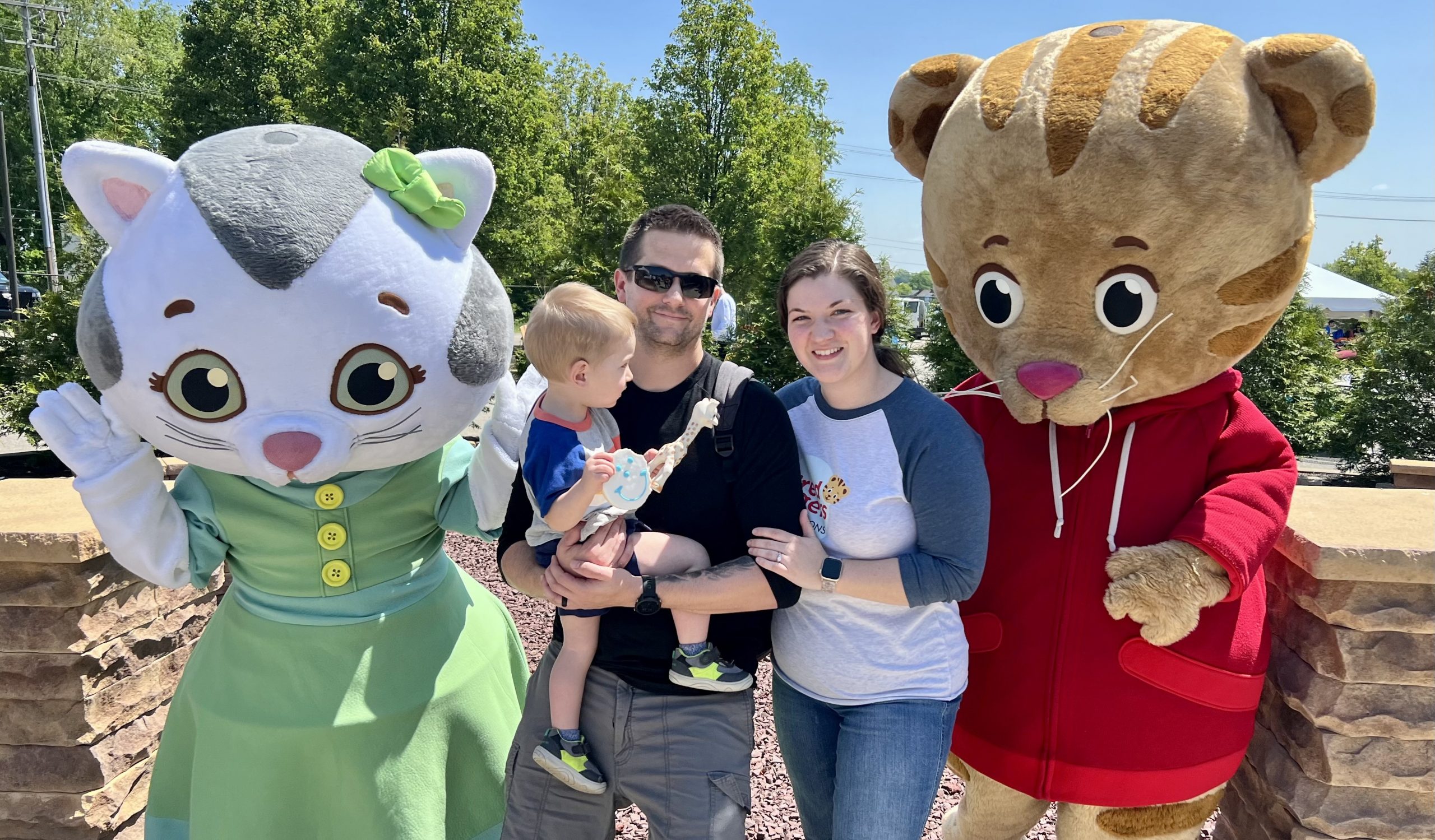 Katerina Kittycat, Daniel Tiger, and a family standing together.